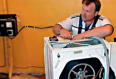 Мастер разбирает стиральную машину для ремонта